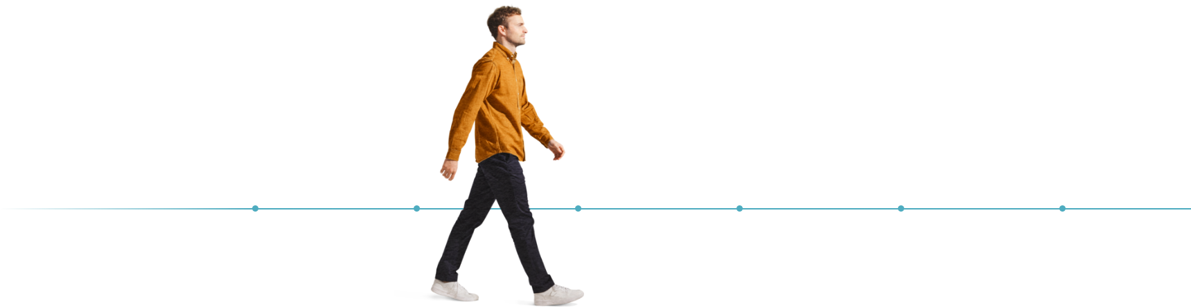 A male wearing a yellow long sleeve shirt, dark jeans, and white shoes walking